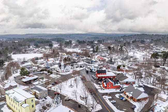 Aerial Winter Snowy Town Center Brick Buildings in Raymond, NH